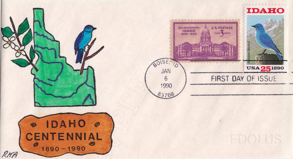 Hand-drawn cachet by RKA featuring a green silhouette of Idaho state map with a blue Mountain Bluebird perched on a branch with white flowers, above an orange plaque reading 'Idaho Centennial 1890-1990'. Two stamps are affixed: a purple 3-cent 1940 Idaho 50th Anniversary stamp showing the state cap…